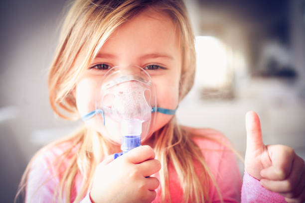Inhaler. Smiling little girl using inhaler and showing OK. medical oxygen stock pictures, royalty-free photos & images