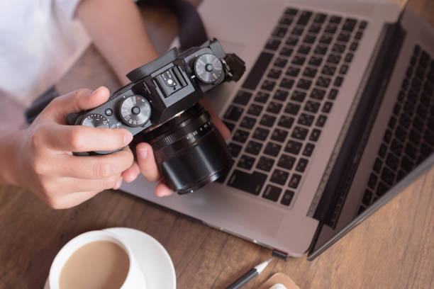 istock Young female photographer checking image on camera on work desk in home office. Professional photographer concept. 896046144