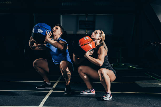 couple squatting with weighted balls