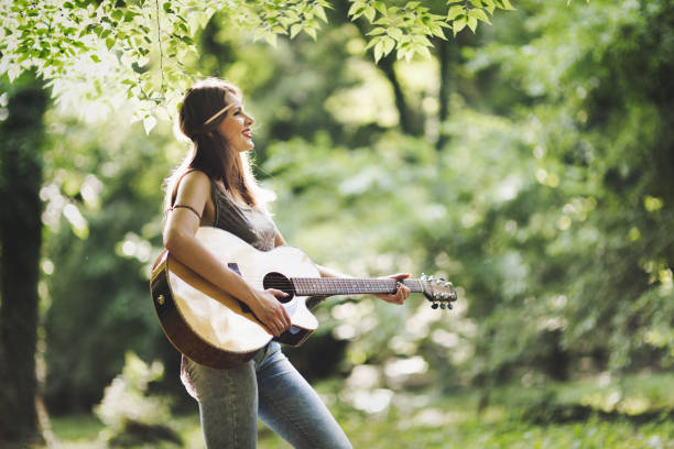 istock Beautiful woman playing guitar in nature 896058704