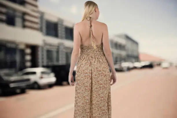 Photo of Attractive young blond woman with stylish open back dress on a street shot from behind