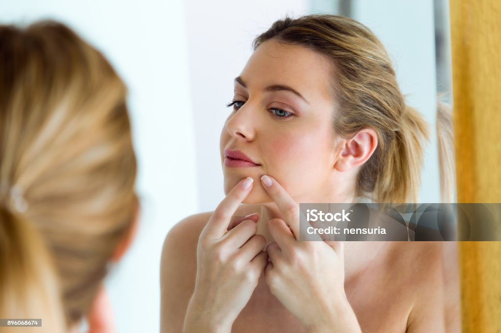 美しい若い女性の家の浴室の彼女の顔からにきびを削除します。 - にきびのロイヤリティフリーストックフォト