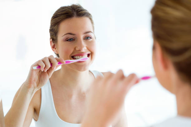 ładna młoda kobieta mycie zębów w łazience w domu. - healthy lifestyle toothbrush caucasian one person zdjęcia i obrazy z banku zdjęć