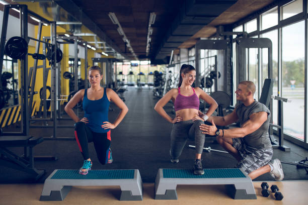 istock Young women doing lunges on step aerobics equipment at gym 896076308