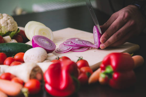 istock Close-up of the man hands while cutting red onion. 896076682