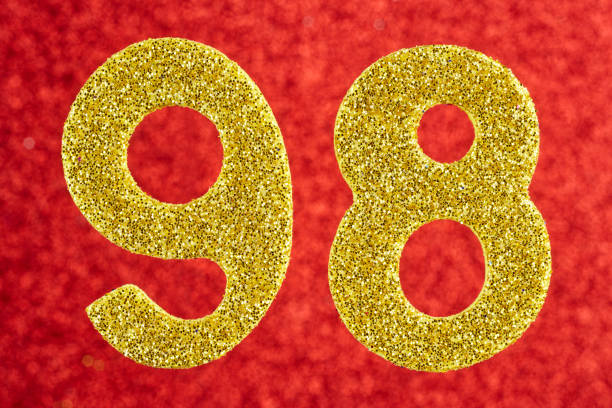 istock Number ninety-eight gold color over a red background. Anniversary. Horizontal 896077030