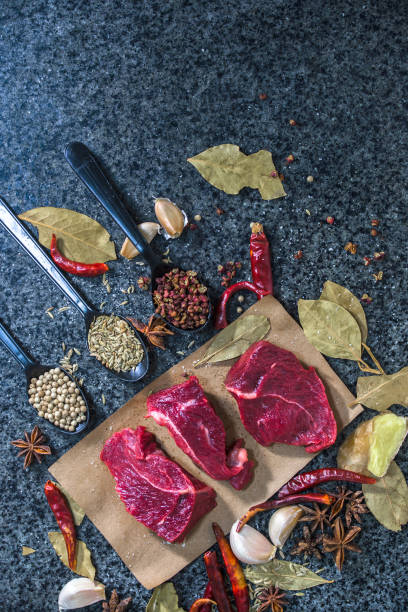 Raw meat. Raw beef steak on a cutting board with rosemary and spices.