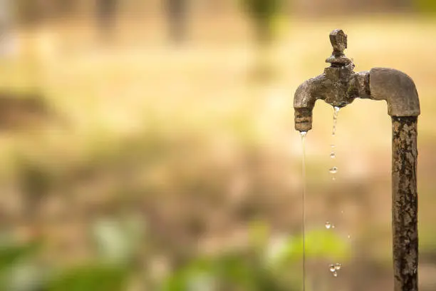 Photo of Falling water from old rusty tap. selective focus, shallow depth of field.