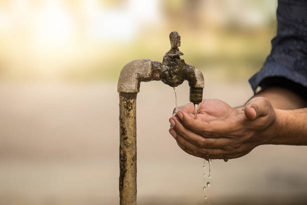 Cupped Hands under falling water from old rusty tap. selective focus, shallow depth of field. Cupped Hands under falling water from old rusty tap. selective focus, shallow depth of field. india poverty stock pictures, royalty-free photos & images