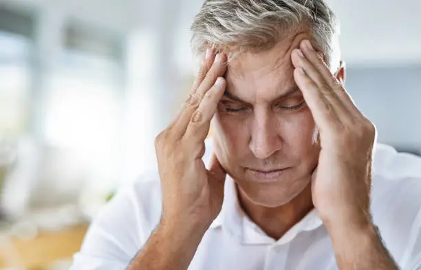 Shot of a mature businessman suffering with a headache at work