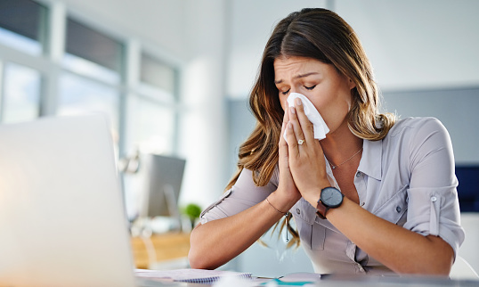 Cropped shot of a businesswoman working in her office while suffering from allergies