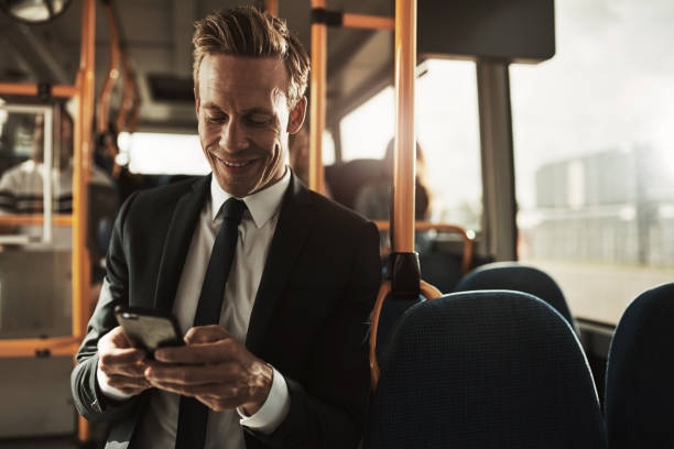 istock Smiling young businessman standing on a bus sending text messsages 896132924