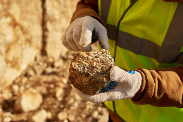 Miner Holding Chunk of Mineral Close up of industrial worker holding mineral ore in gloved hands on mining site, copy space mineral stock pictures, royalty-free photos & images