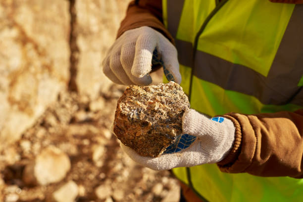 Miner Holding Chunk of Mineral Close up of industrial worker holding mineral ore in gloved hands on mining site, copy space gold mine stock pictures, royalty-free photos & images