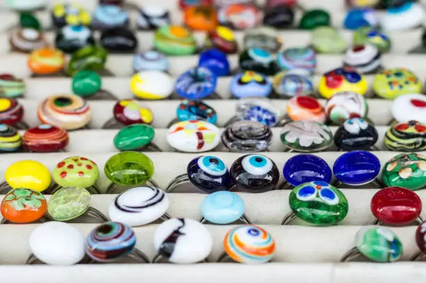 Selection of colorful glass rings made in glassblowing workshop by masters displayed in a store.