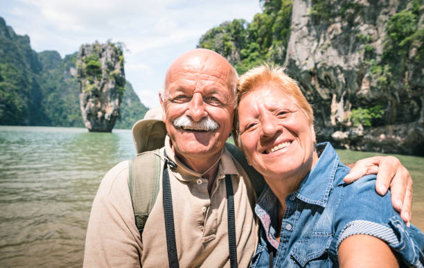 istock Happy retired senior couple taking travel selfie around world - Active elderly concept with people having fun together at James Bond Island in Thailand - Mature people lifestyle - Warm day filter 896180618