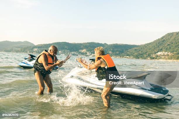 Senior Happy Couple Having Playful Fun At Jet Ski On Beach Island Hopping Tour Active Elderly Travel Concept Around The World With Retired People Riding Water Scooter Jetski Bright Vintage Filter Stock Photo - Download Image Now