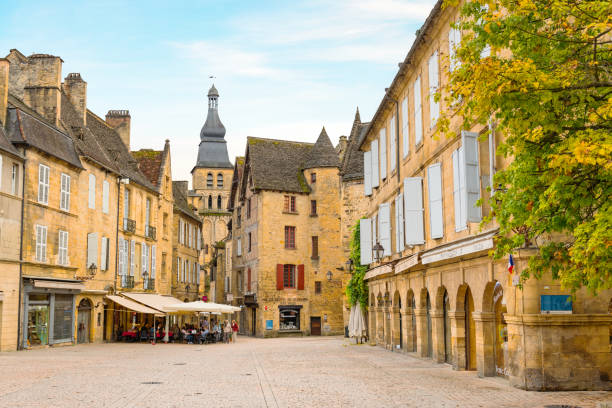 Historic village Sarlat La Caneda Sarlat-la-caneda, France - October 02, 2017: View from the town center of the historic village Sarlat-la-caneda with cafe and restaurants and  the tower of the Saint-Sacerdos Cathedral, in the region called the Dordogne in the South West of France. sarlat la caneda stock pictures, royalty-free photos & images