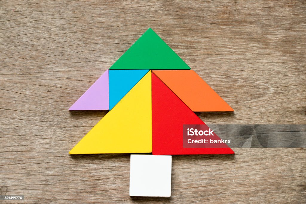 Colorful tangram puzzle in Pine or christmas tree shape on wood background Christmas Stock Photo