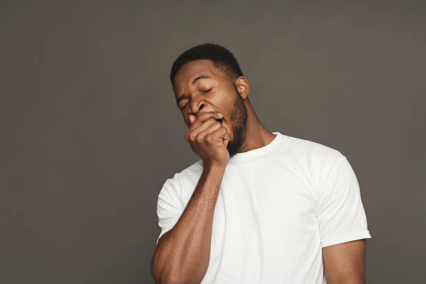 Facial expression, emotions, friendly black man yawning Black man yawning on grey background, studio shot, copy space yawning stock pictures, royalty-free photos & images