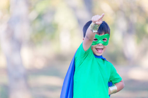 istock Little boy in superhero costume points at the sky 896216626
