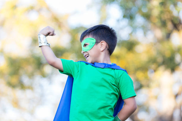 istock Little boy in superhero costume poses with flexed muscles 896216708