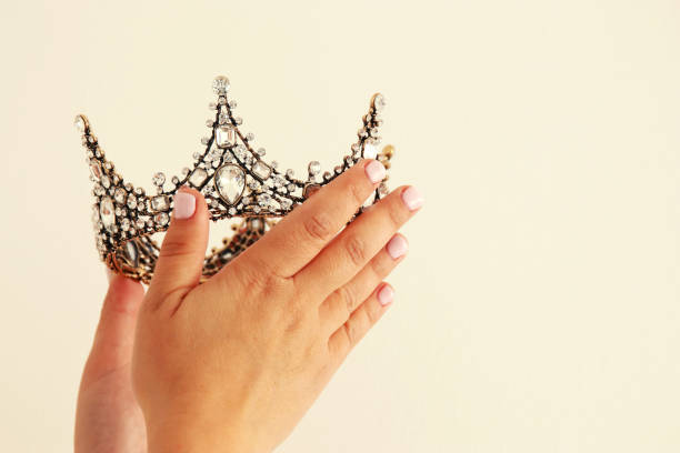 istock Woman's hand holding a crown for show victory or winning first place. White background. Copy space. Isolated. 896221048