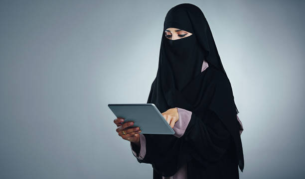 Familiarising herself with her new tablet’s functions Studio shot of a young woman wearing a burqa and using a digital tablet against a gray background familiarising stock pictures, royalty-free photos & images