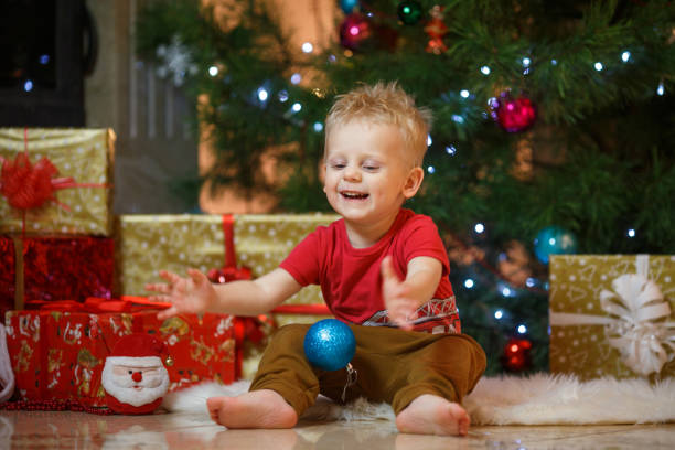 かわいい金髪の暖炉とクリスマス ツリーの下のプレゼントの近くの小さな男の子 - gift little boys people blond hair ストックフォトと画像