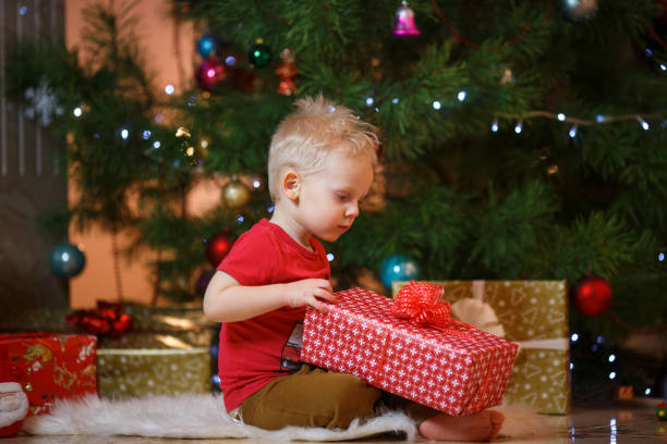 ブロンドの髪がかわいいクリスマス ツリーとギフト ボックスの近くに小さな少年 - gift little boys people blond hair ストックフォトと画像