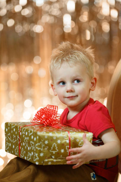かわいい金髪少年が贈り物を続けています。 - gift little boys people blond hair ストックフォトと画像