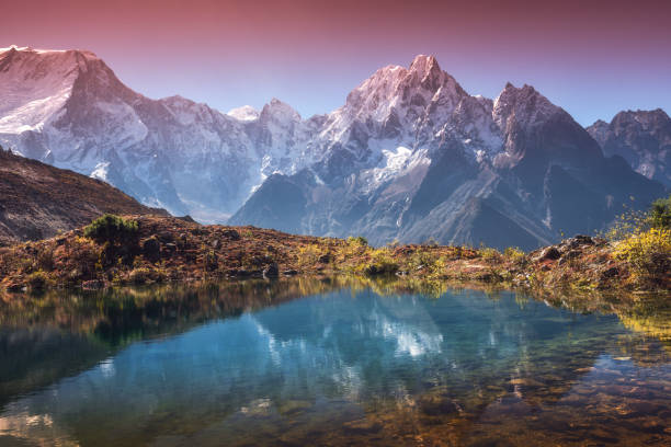 bellissimo paesaggio con alte montagne con cime innevate, cielo riflesso nel lago. valle di montagna con riflessione in acqua all'alba. nepal. scena incredibile con montagne himalayane. natura - himalayas foto e immagini stock