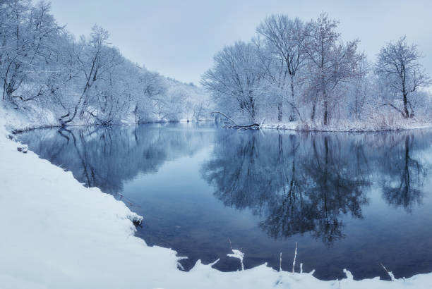istock Winter forest on the river at sunset. Colorful landscape with snowy trees, river with reflection in water in cold evening. Snow covered trees, lake, sun and blue sky. Beautiful forest in snowy winter 896245356