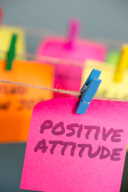 istock A bright pink sticky note with the text Positive Attitude hung from a clothesline by a blue clothespin. 896259568