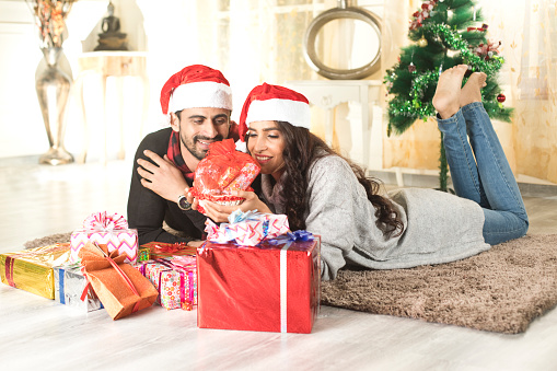 Young Couple lying on carpet with Santa hat and Christmas present