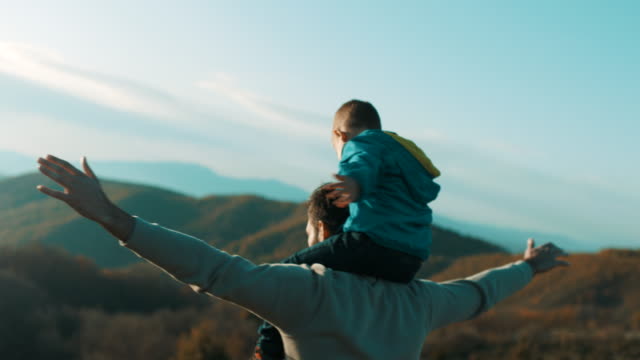 Father carrying son on shoulders at top of the mountain
