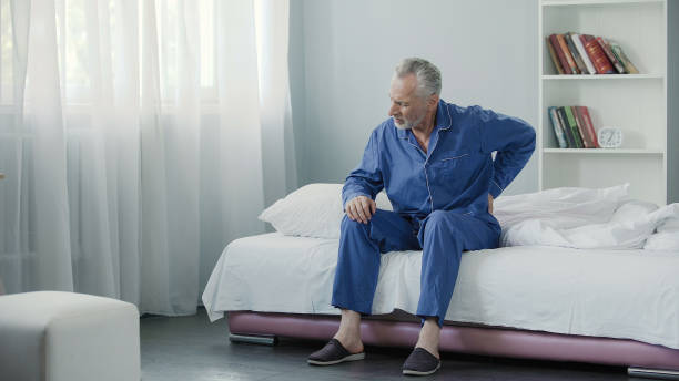 istock Senior male suffering sharp back pain, getting up from bed, morning 896270448
