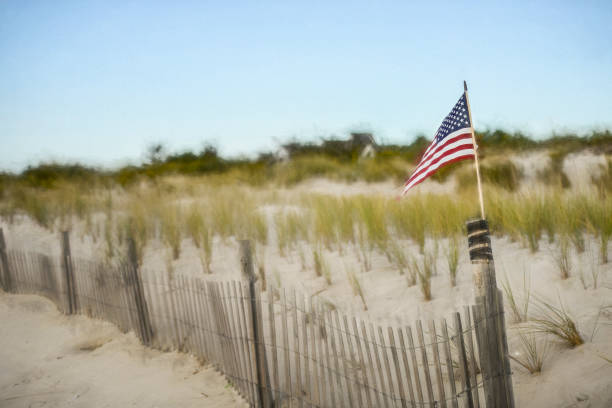 An American flag waving on a white sand beach