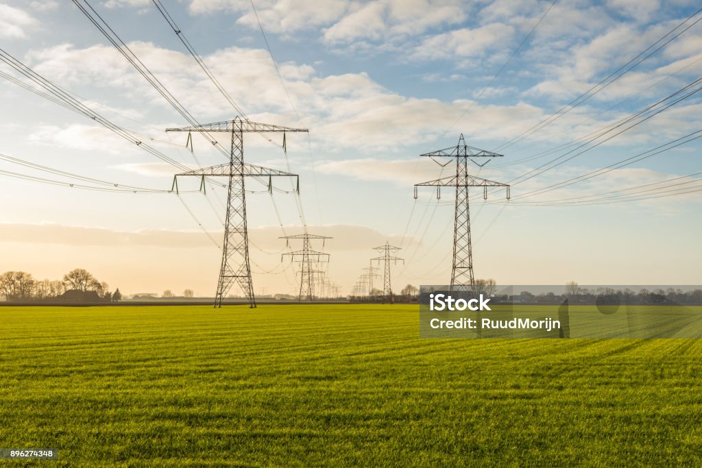 Dos líneas convergentes de alta tensión en una zona rural - Foto de stock de Cable de conducción eléctrica libre de derechos