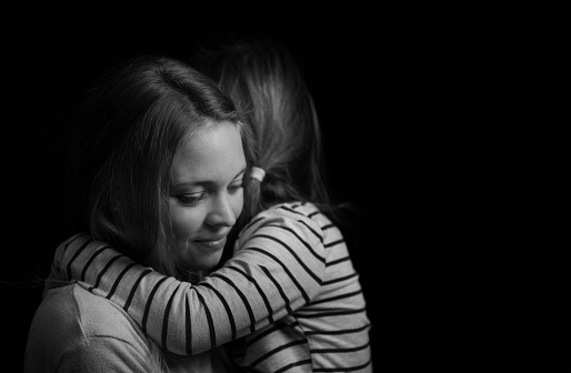 Low key picture of friends hugging each other in front of a black background