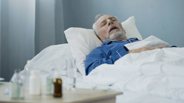 istock Old man sleeping in bed at hospital ward, antibiotics standing on the table 896288610