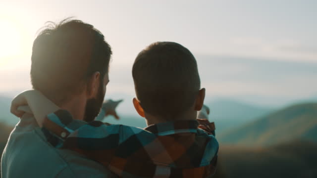 Father holding young son in his arms on top of the mountain