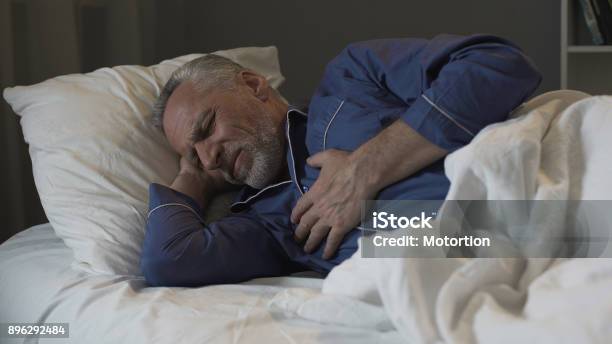 Male Pensioner Having Heart Attack Suffering Sharp Chest Pain While Sleeping Stock Photo - Download Image Now