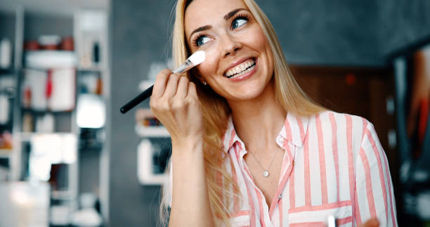 maquilleuse application teint tonale liquide sur le visage de la femme en maquillage chambre - make up foundation cosmetics face powder photos et images de collection