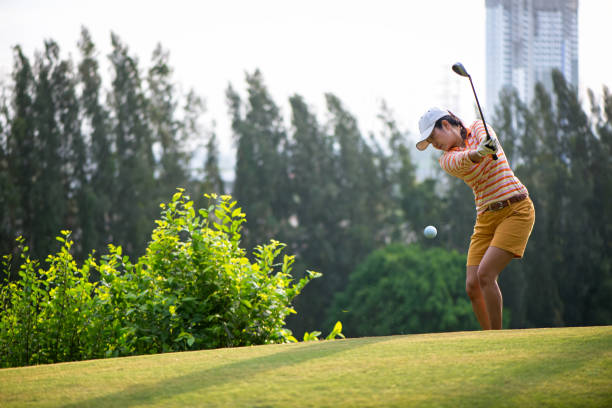 azjatka golfista uderzenie chipy piłkę golfową do otworu na zielono z klubu golfowego w słoneczny dzień, skopiować miejsce.  koncepcja stylu życia. - chipping zdjęcia i obrazy z banku zdjęć