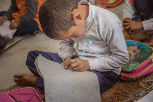 istock Concentrated Rural school kid studying on floor and writing in the notebook. 896301862