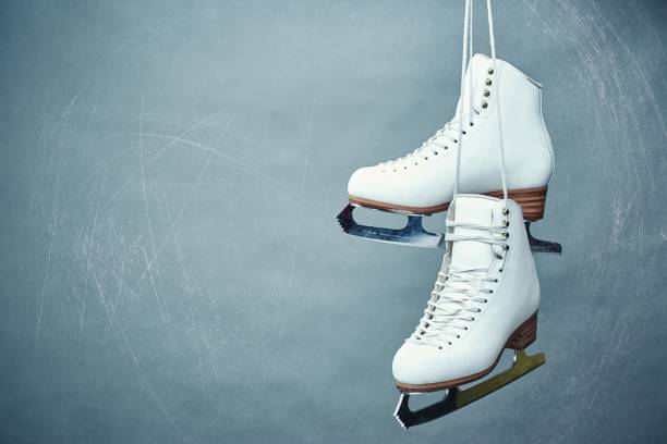 Women's skates with laces on a gray background. A pair of female white skates on a gray background. figure skating stock pictures, royalty-free photos & images