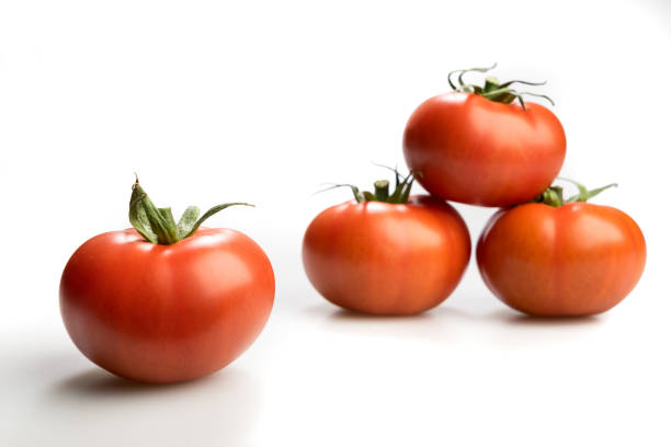 istock Four realistic looking tomatoes lying piled up isolated in a white background 896319050