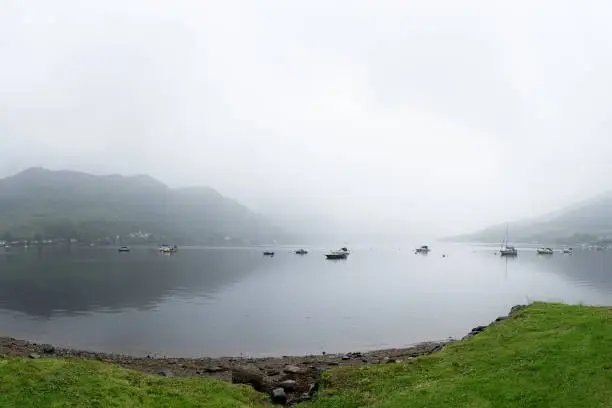 Loch view on Loch Goilhead with boats and mist on a gloomy sommerday, Scotland, Great-Britain