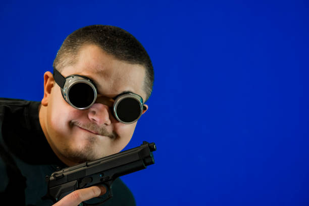 the face of a young man with a changing facial expression. satisfied face of a robber or a thief with a gun. - spy gun men humor imagens e fotografias de stock